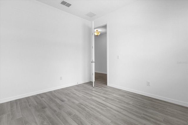 empty room featuring wood finished floors, visible vents, and baseboards