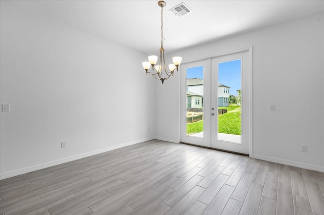 spare room with visible vents, baseboards, french doors, wood finished floors, and a notable chandelier