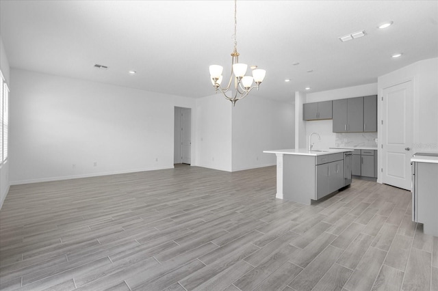 kitchen with visible vents, gray cabinetry, an inviting chandelier, and a sink