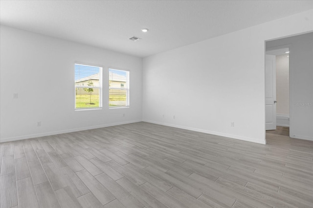 empty room featuring baseboards, visible vents, and light wood finished floors