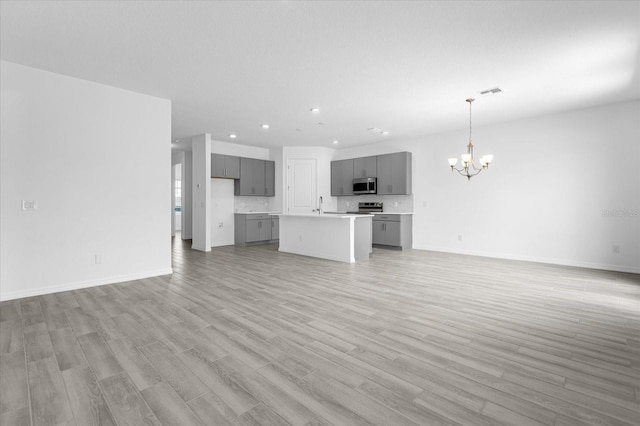 unfurnished living room with visible vents, baseboards, a chandelier, recessed lighting, and light wood-style floors