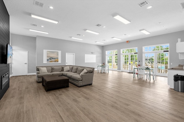 living area featuring light wood finished floors, visible vents, and french doors