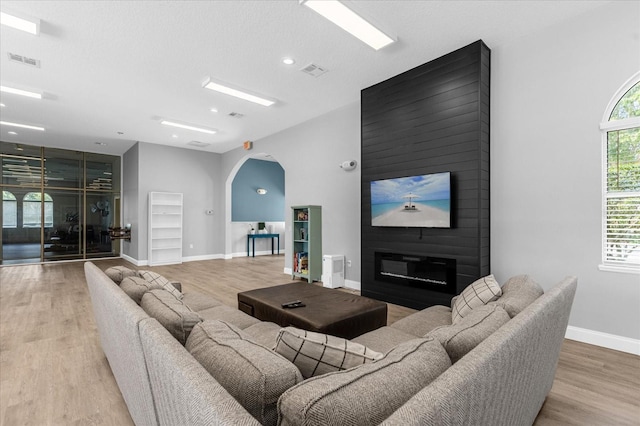 living area with visible vents, arched walkways, baseboards, and wood finished floors