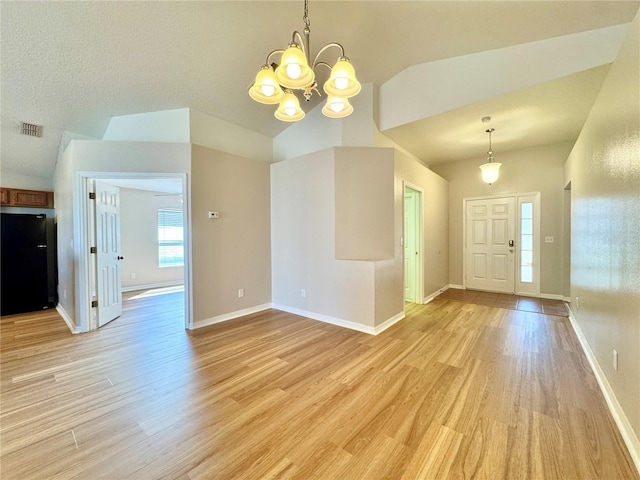 foyer entrance with visible vents, lofted ceiling, a chandelier, and light wood-style flooring