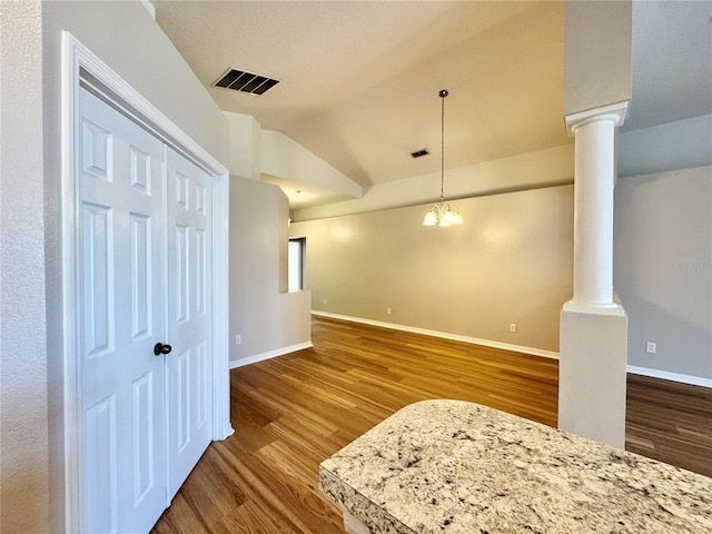 interior space featuring visible vents, decorative columns, lofted ceiling, and wood finished floors