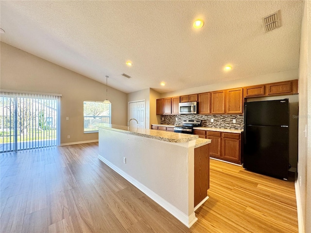 kitchen featuring visible vents, stainless steel appliances, vaulted ceiling, light countertops, and brown cabinets