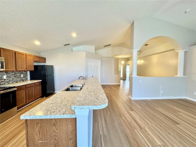 kitchen featuring lofted ceiling, open floor plan, stainless steel appliances, and a sink