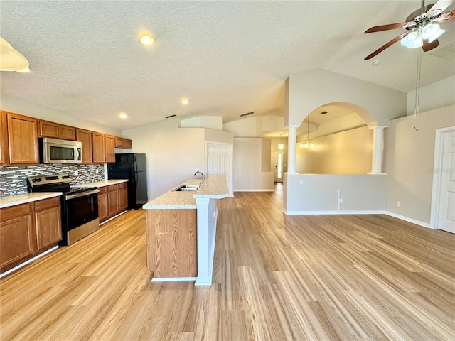 kitchen with brown cabinets, appliances with stainless steel finishes, lofted ceiling, and ceiling fan