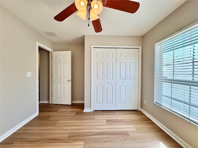 unfurnished bedroom with a closet, visible vents, light wood-type flooring, and baseboards