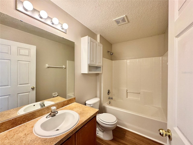 bathroom with visible vents, toilet, a textured ceiling, wood finished floors, and vanity