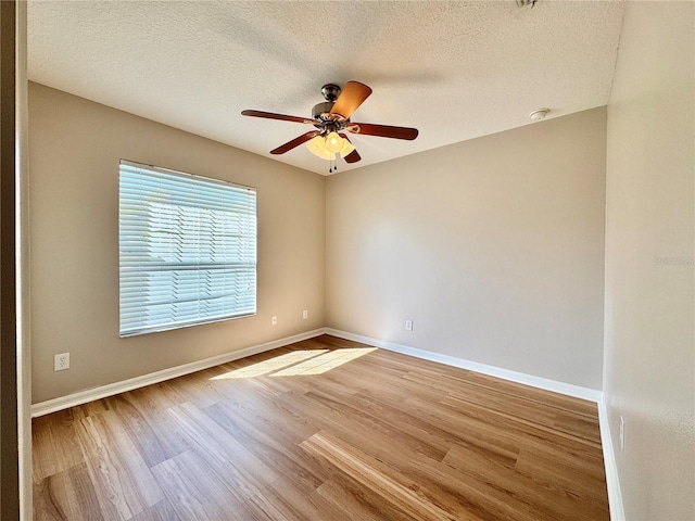 empty room with baseboards, a textured ceiling, wood finished floors, and a ceiling fan