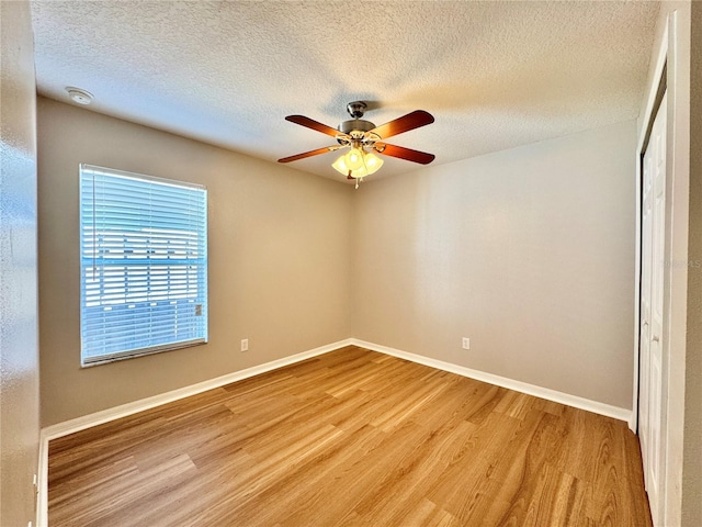 unfurnished room featuring a textured ceiling, a ceiling fan, light wood-style floors, and baseboards