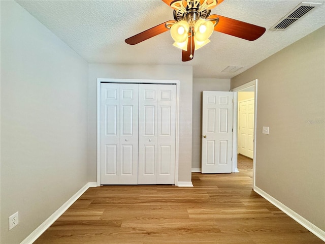 unfurnished bedroom with a closet, visible vents, light wood-type flooring, and baseboards