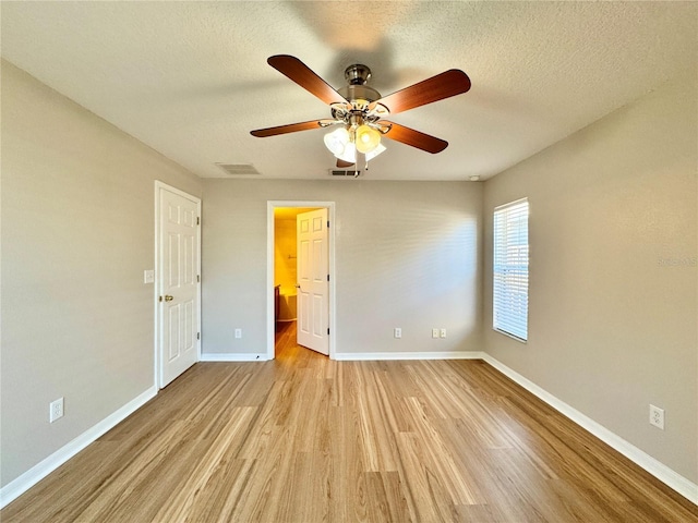 unfurnished bedroom featuring a textured ceiling, light wood-style floors, visible vents, and baseboards