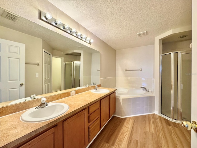 bathroom featuring a sink, wood finished floors, a bath, and a shower stall