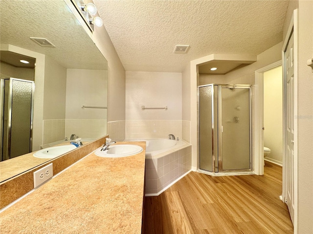 full bathroom with visible vents, a shower stall, toilet, a garden tub, and wood finished floors