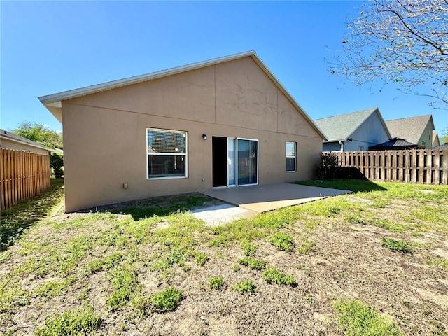 rear view of property with a patio area, a yard, stucco siding, and fence