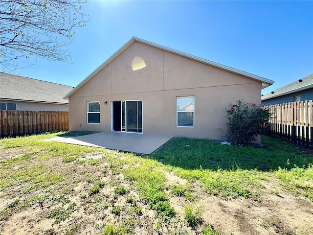 back of house with a yard, a fenced backyard, stucco siding, and a patio area