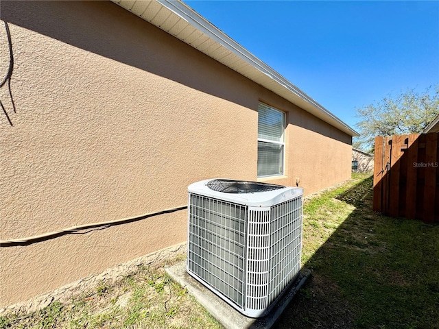 details with central air condition unit, fence, and stucco siding