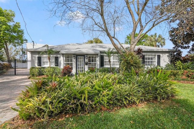 ranch-style home with decorative driveway and a gate