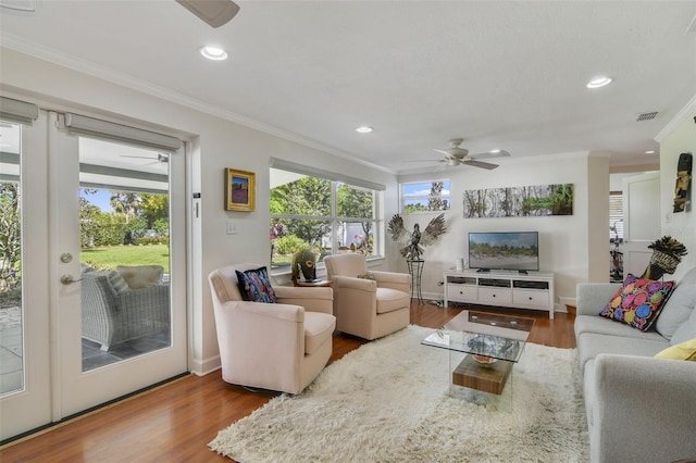 living area with visible vents, plenty of natural light, wood finished floors, and a ceiling fan