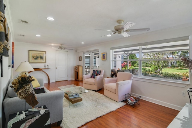 living area with visible vents, ornamental molding, ceiling fan, and wood finished floors