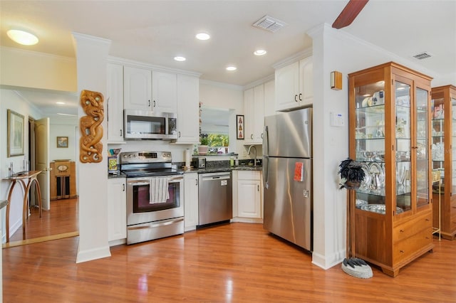 kitchen featuring ornamental molding, appliances with stainless steel finishes, white cabinetry, and a sink