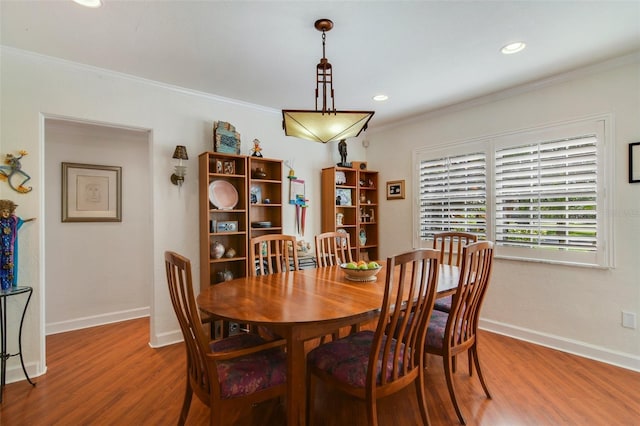 dining area featuring crown molding, baseboards, and wood finished floors