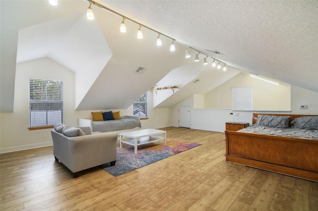 bedroom with visible vents, a textured ceiling, lofted ceiling, and wood finished floors