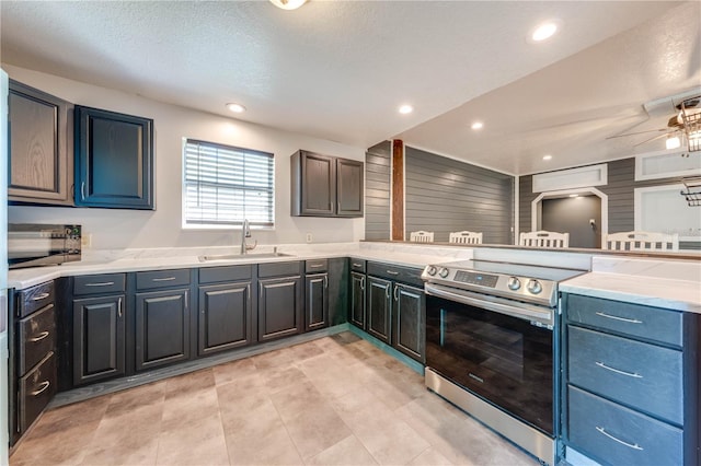 kitchen with electric range, a ceiling fan, a sink, recessed lighting, and light countertops