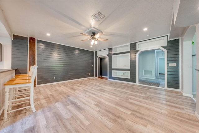 unfurnished living room with baseboards, visible vents, light wood-style flooring, arched walkways, and ceiling fan