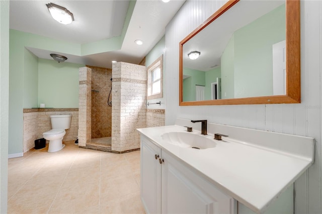 full bath with tile patterned flooring, tile walls, walk in shower, toilet, and vanity