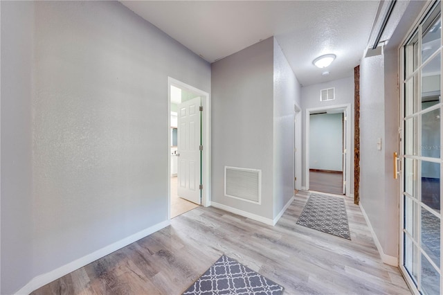 corridor featuring wood finished floors, visible vents, and baseboards