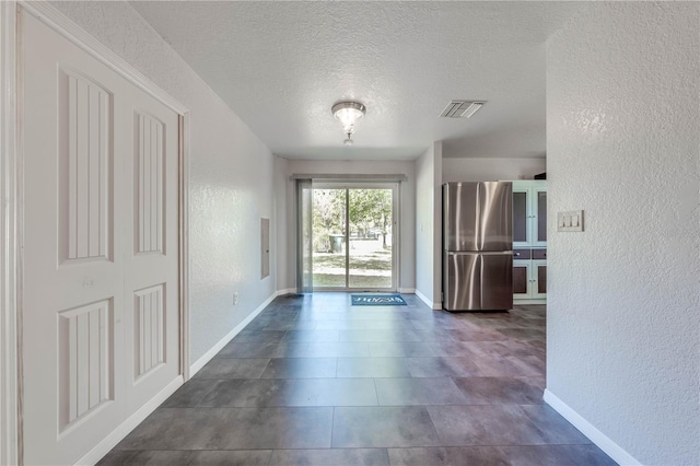 interior space with visible vents, a textured ceiling, baseboards, and a textured wall