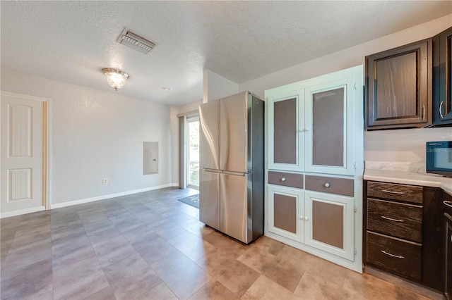 kitchen featuring visible vents, dark brown cabinets, light countertops, and freestanding refrigerator