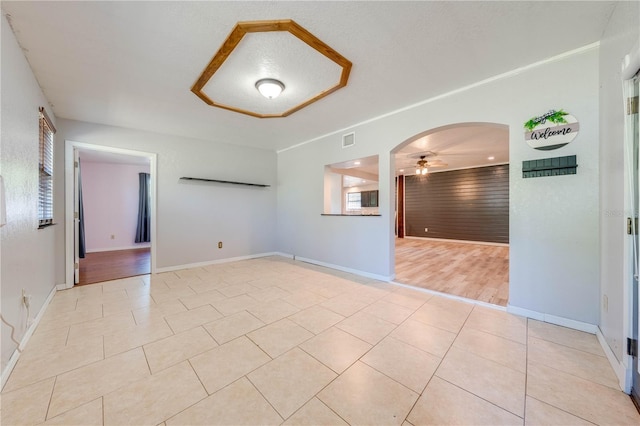 spare room featuring light tile patterned floors, visible vents, baseboards, and a ceiling fan