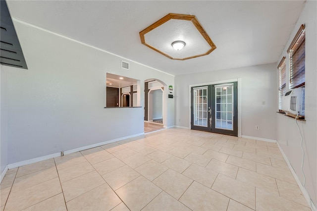 tiled spare room with visible vents, baseboards, cooling unit, french doors, and arched walkways