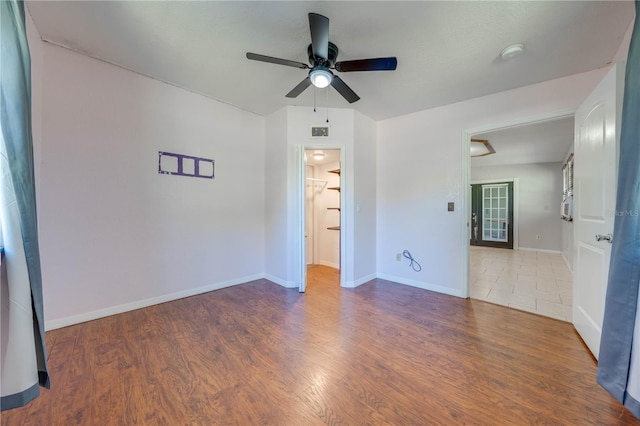 empty room with baseboards, a ceiling fan, and wood finished floors