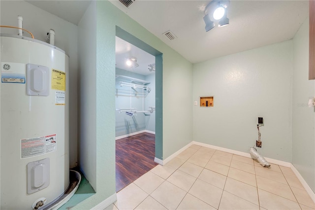 laundry room with visible vents, electric water heater, light tile patterned floors, baseboards, and laundry area