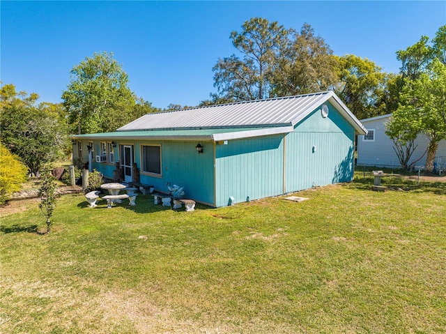 rear view of property featuring a yard and metal roof