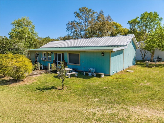 back of property featuring metal roof and a lawn