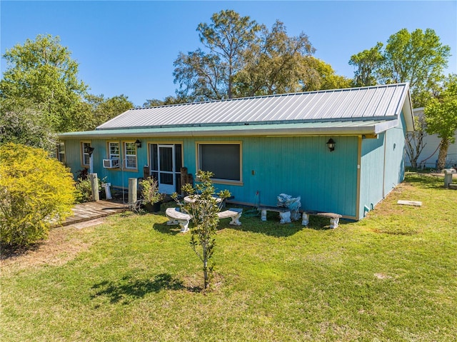 back of property with cooling unit, metal roof, and a yard