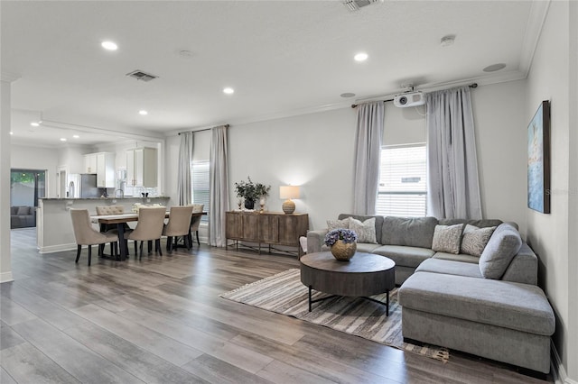 living room featuring crown molding, recessed lighting, wood finished floors, and visible vents