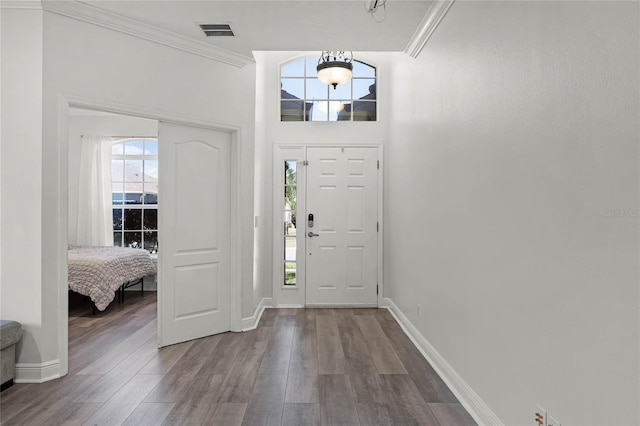 entrance foyer featuring visible vents, baseboards, dark wood finished floors, and ornamental molding