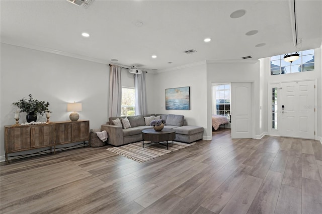 living room with visible vents, recessed lighting, light wood-style floors, a baseboard heating unit, and crown molding