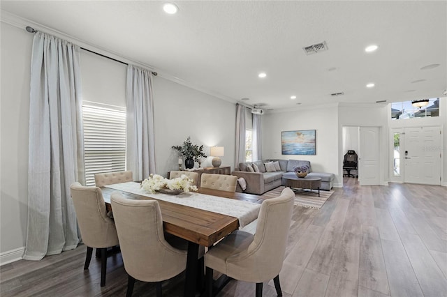 dining area featuring crown molding, wood finished floors, and visible vents