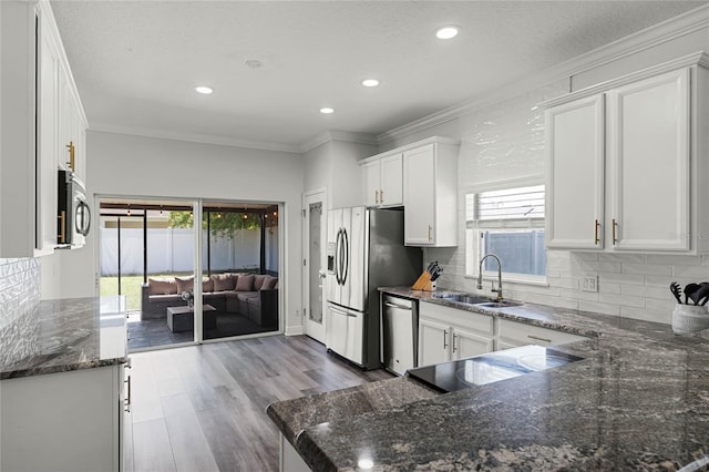 kitchen with white cabinets, ornamental molding, appliances with stainless steel finishes, and a sink