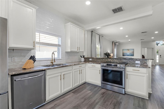 kitchen featuring dark wood-style floors, visible vents, a peninsula, a sink, and appliances with stainless steel finishes