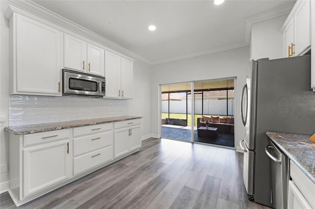 kitchen featuring tasteful backsplash, white cabinets, appliances with stainless steel finishes, and crown molding