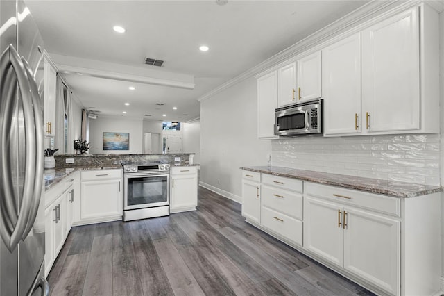 kitchen with a peninsula, backsplash, visible vents, and appliances with stainless steel finishes